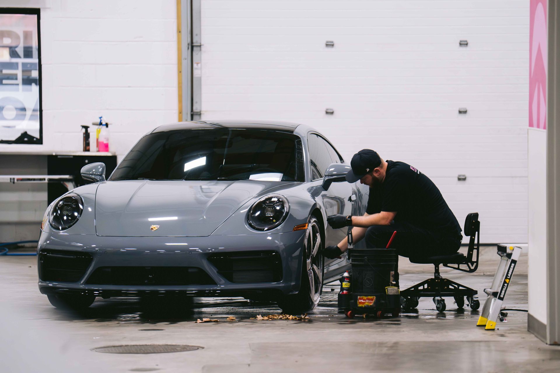 A man is working on a porsche in a garage.