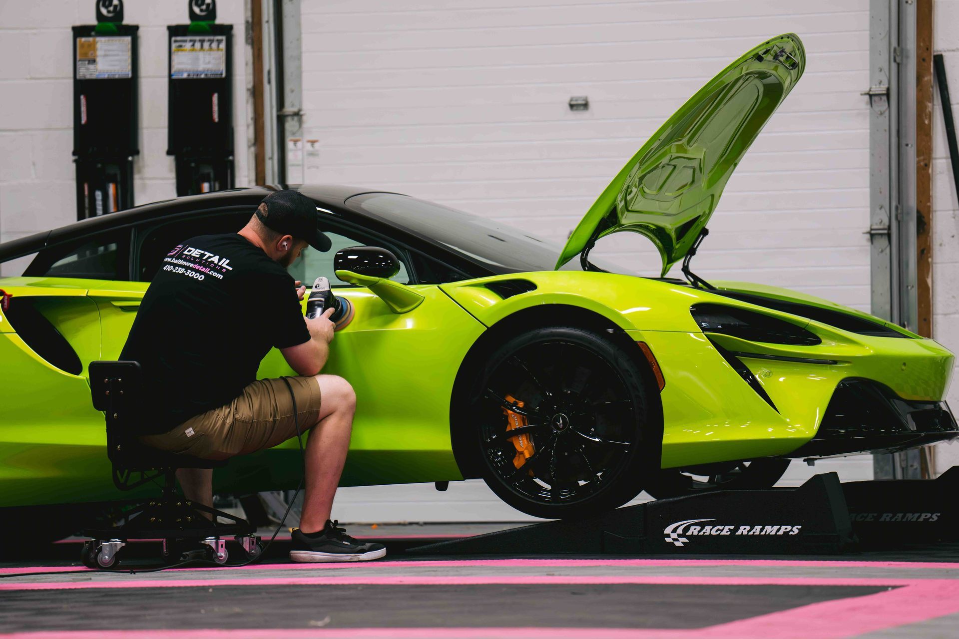 A man is working on a green sports car in a garage.