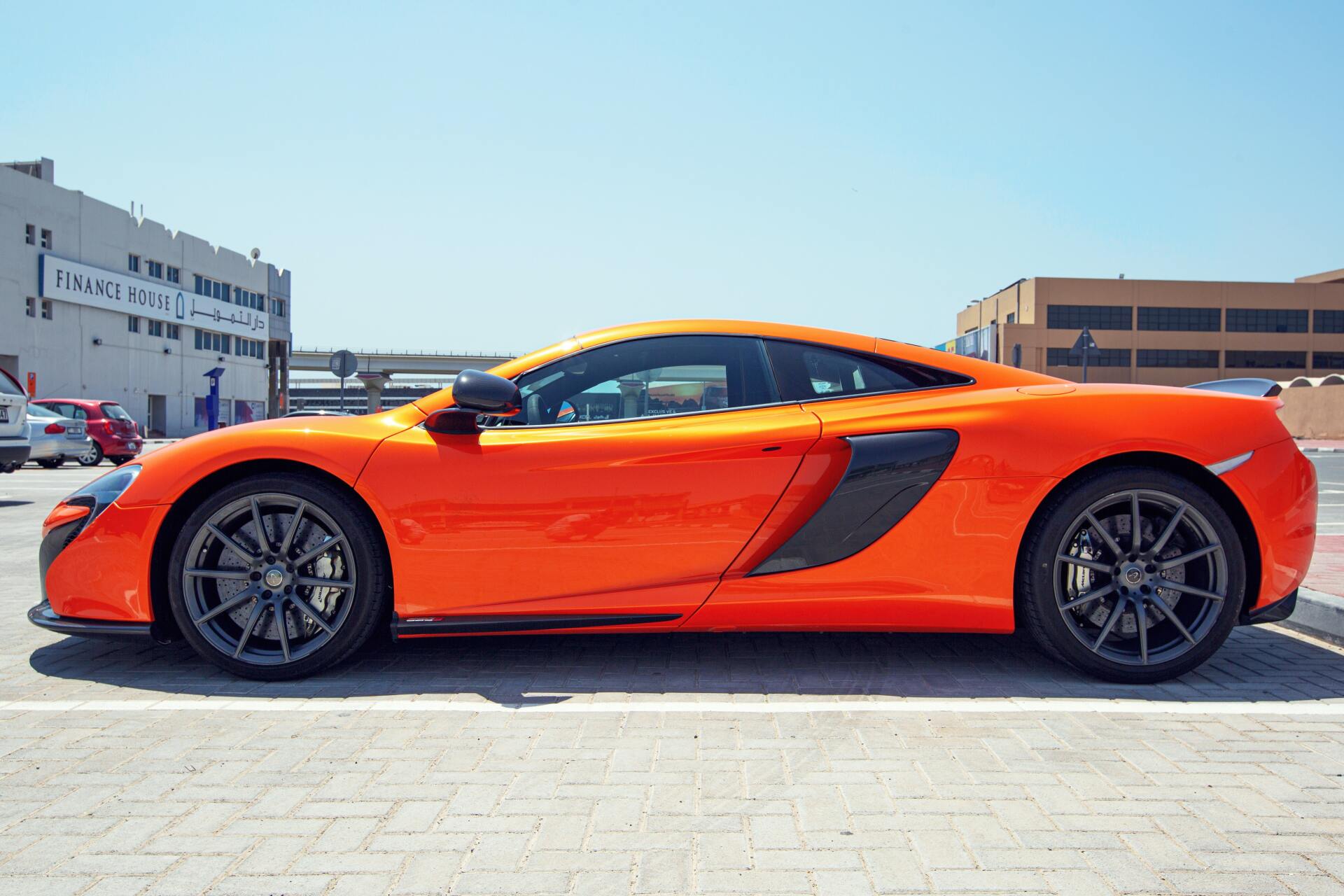 A bright orange sports car is parked in a parking lot.