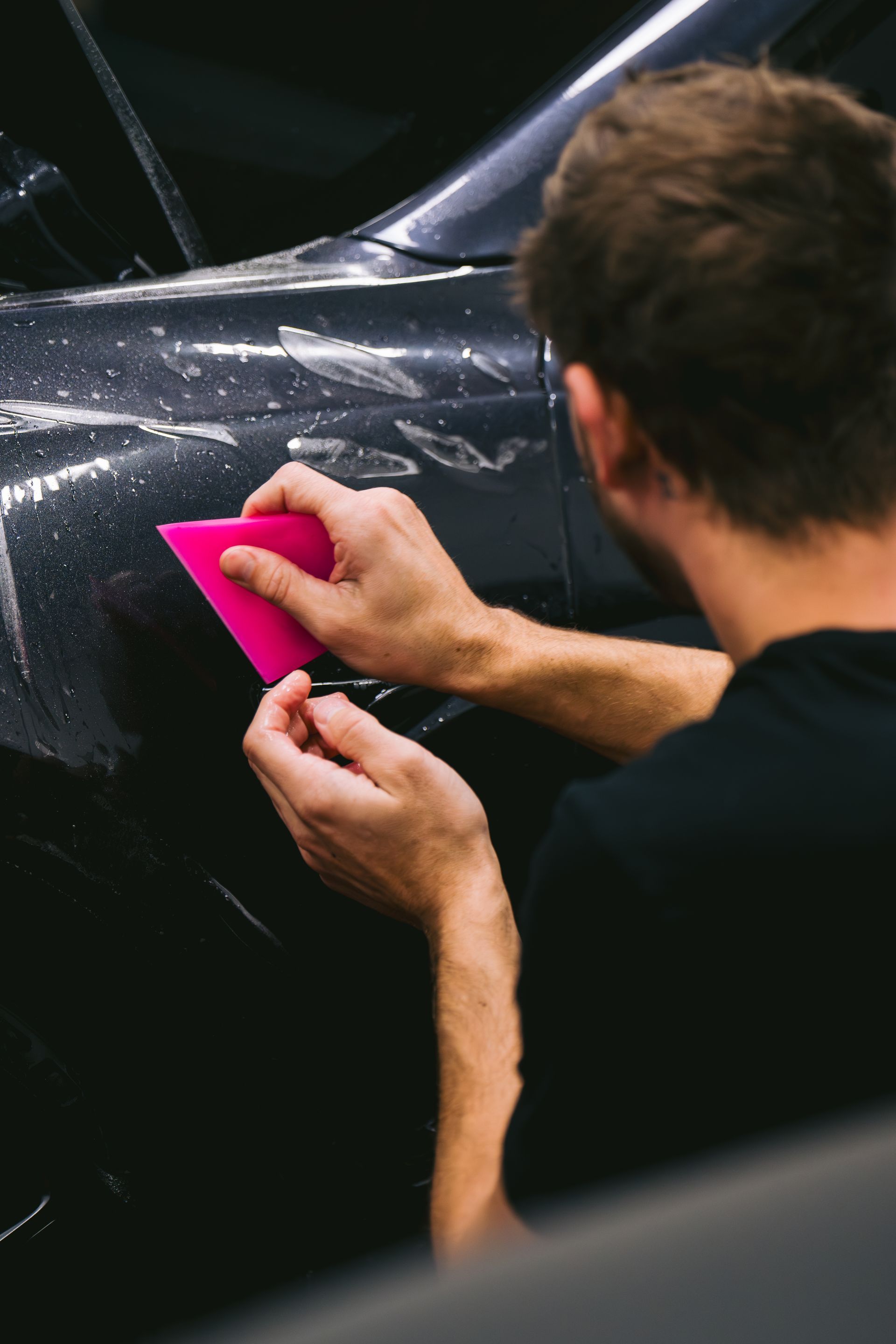 A person is cleaning a car with a blue sponge.