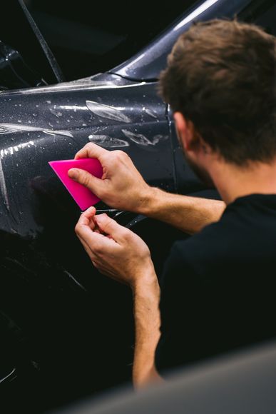 A person is cleaning a car with a blue sponge.
