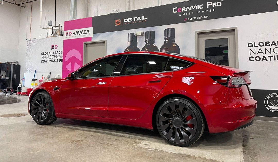 a red tesla model 3 is parked in a garage .
