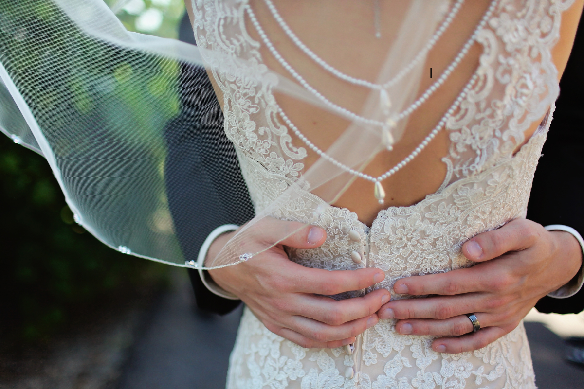 A bride and groom are hugging and the bride is wearing a veil.