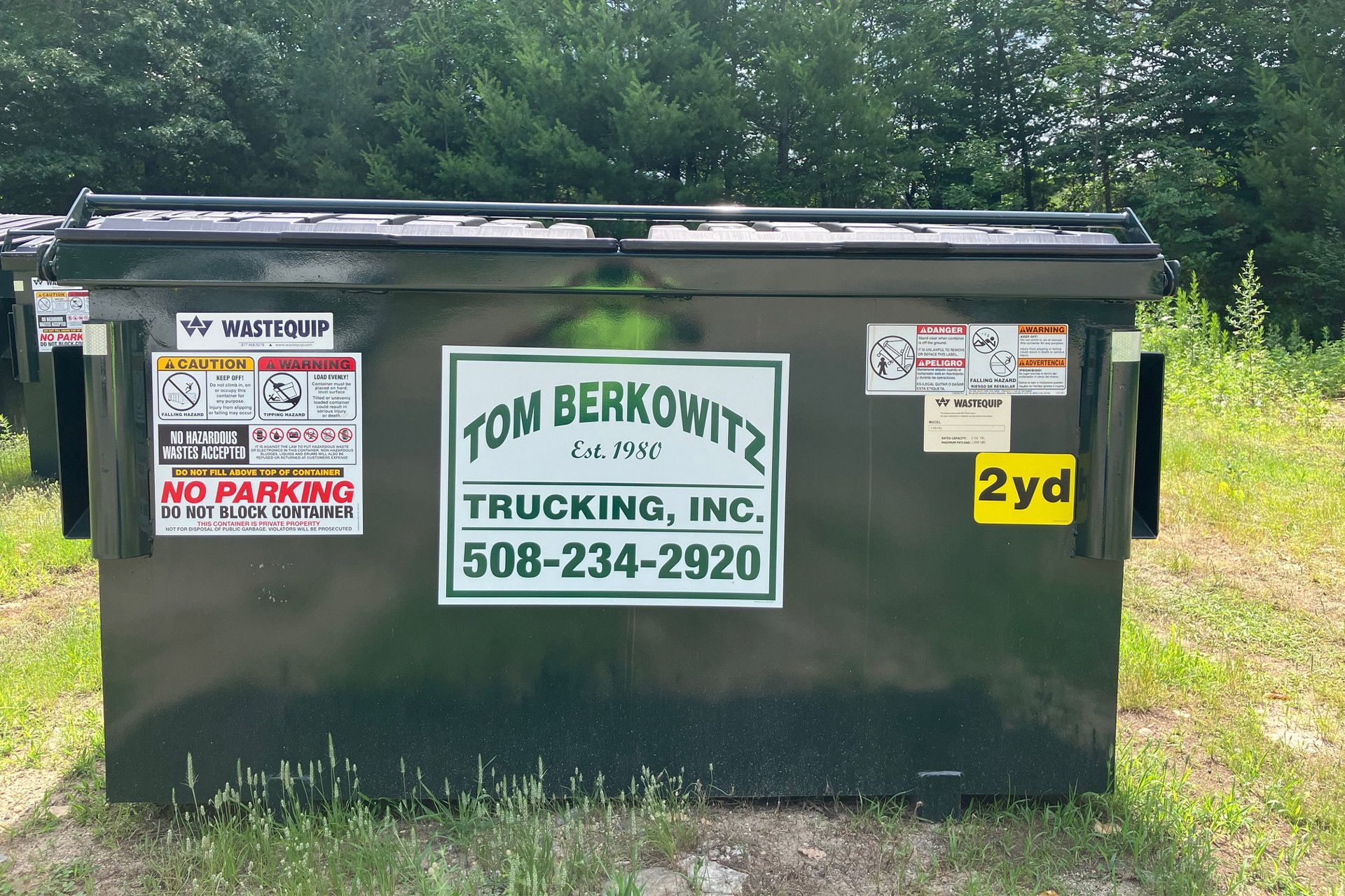 A dark green dumpster with labels, including 