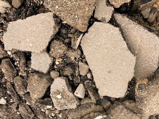 Broken pieces of asphalt, gray and black, scattered on a surface.