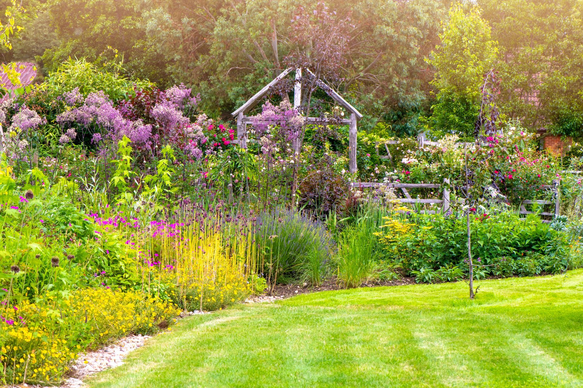A garden with flowers and a brick walkway in front of a house.