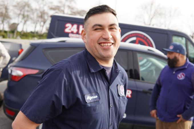 a man in a blue shirt is smiling in front of a 24 hour van .