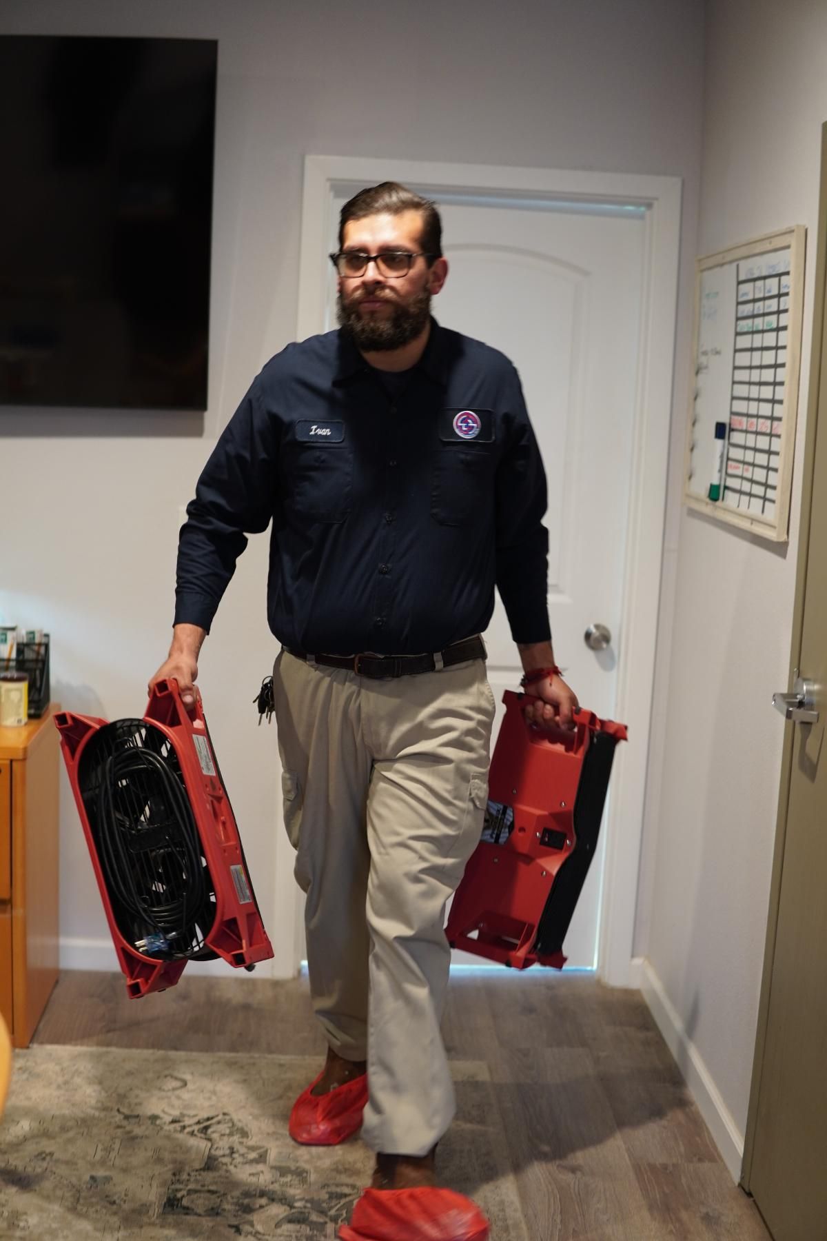 a man is carrying two red boxes in a room .