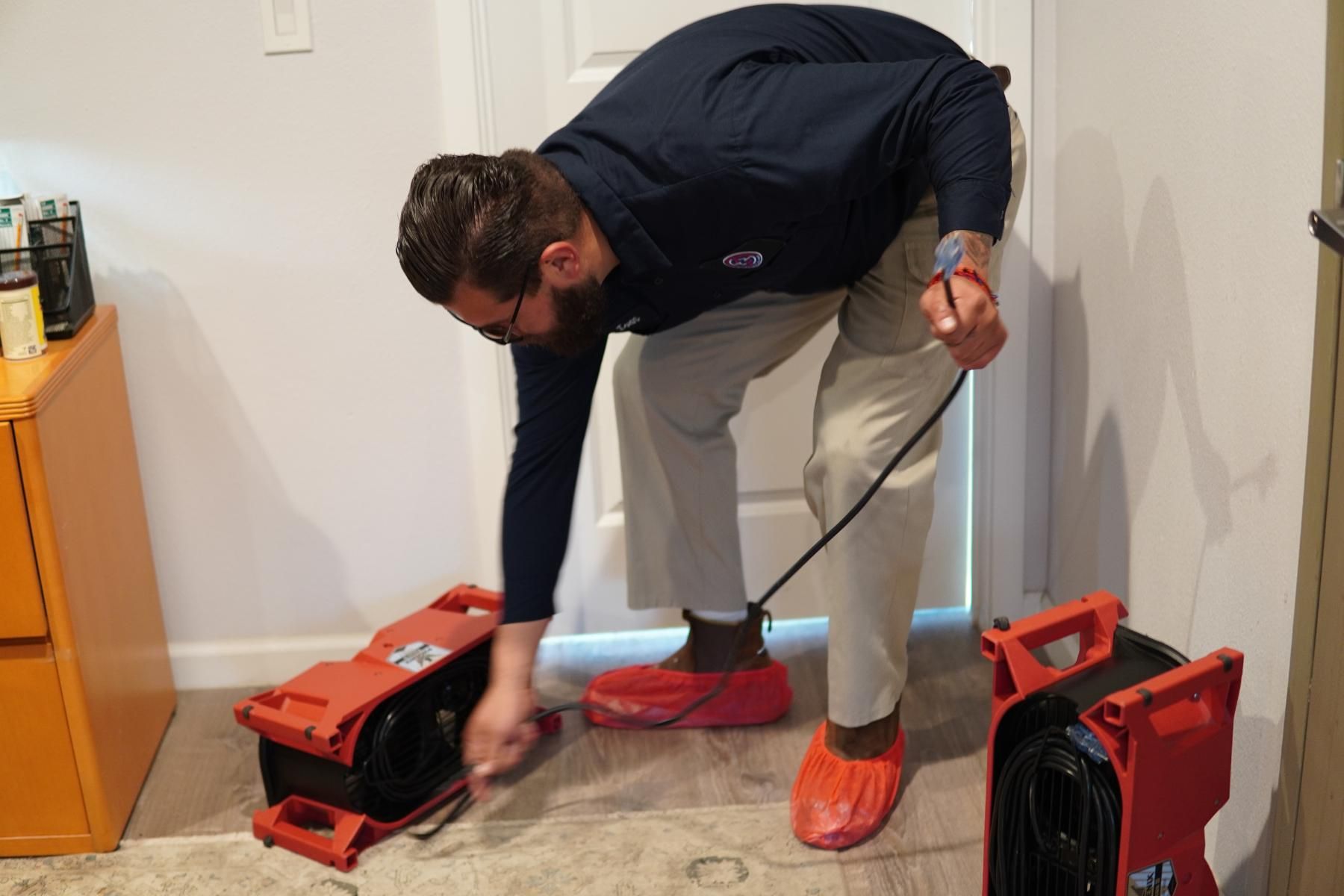 a man is kneeling down in a room next to a fan .