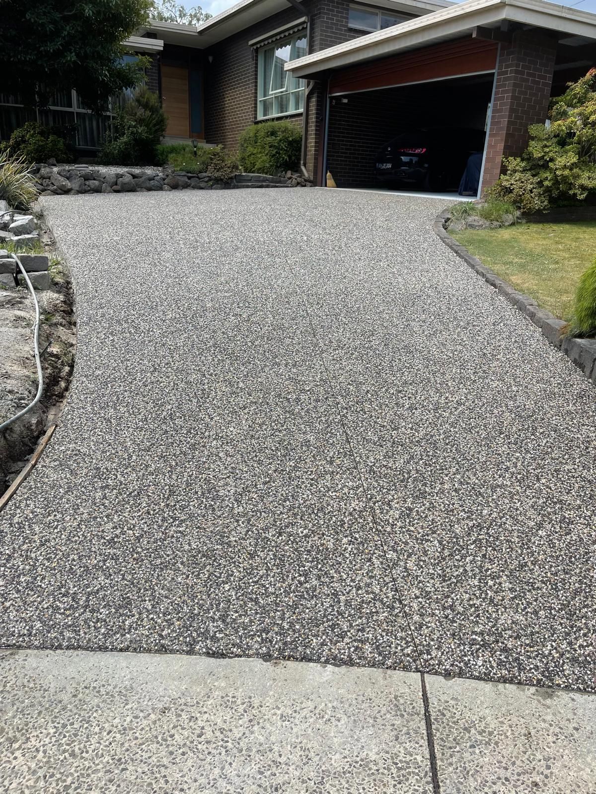 A driveway leading to a house with a car parked in the garage.