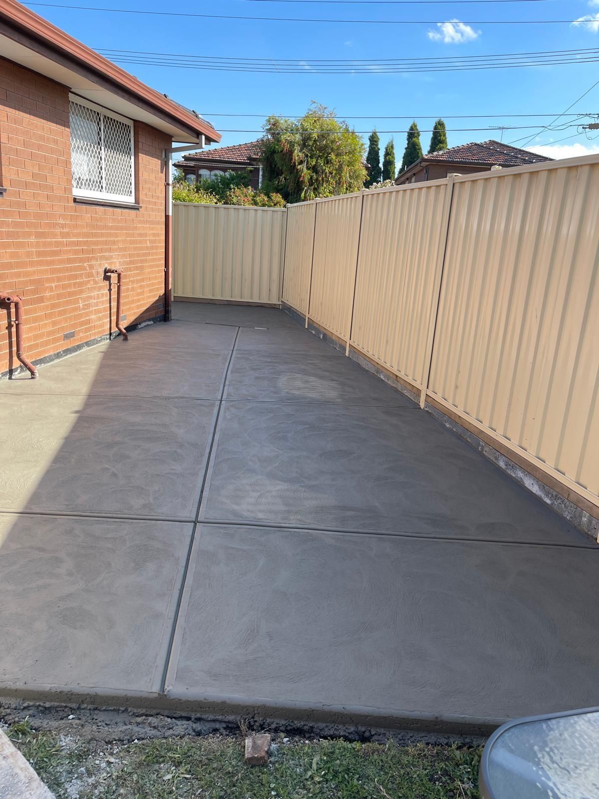 A brick house with a fence and a concrete driveway in front of it.