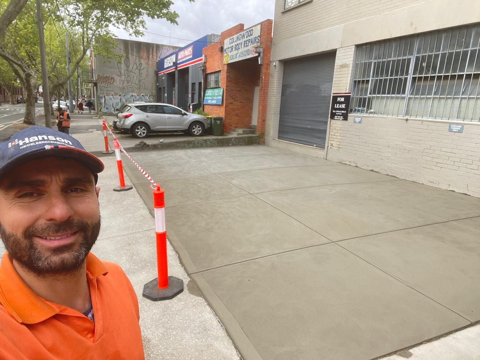 A man is standing on a sidewalk in front of a building.