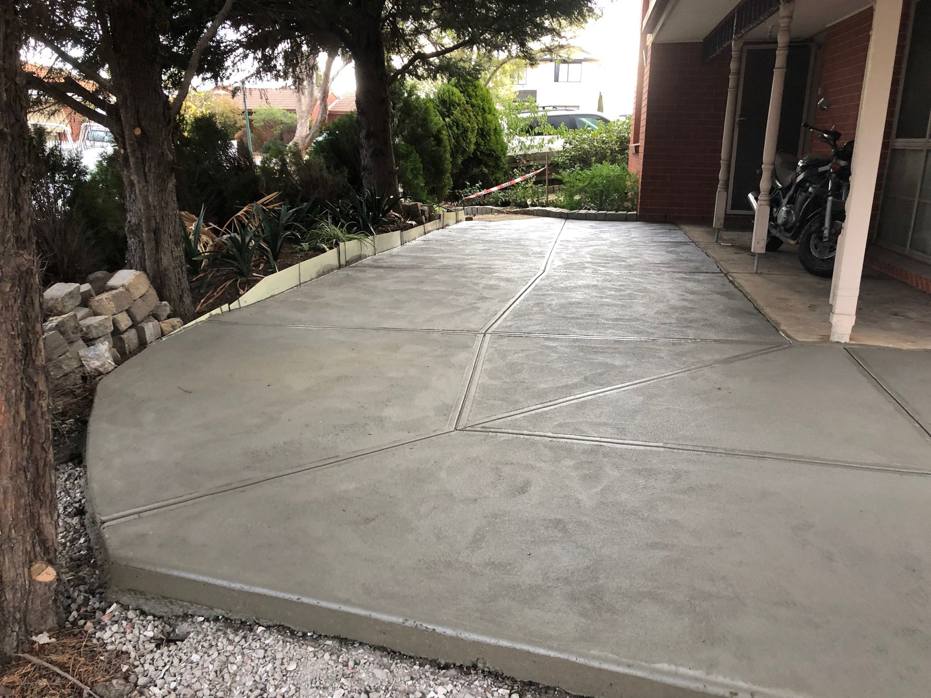 A concrete driveway with a motorcycle parked in front of a house.