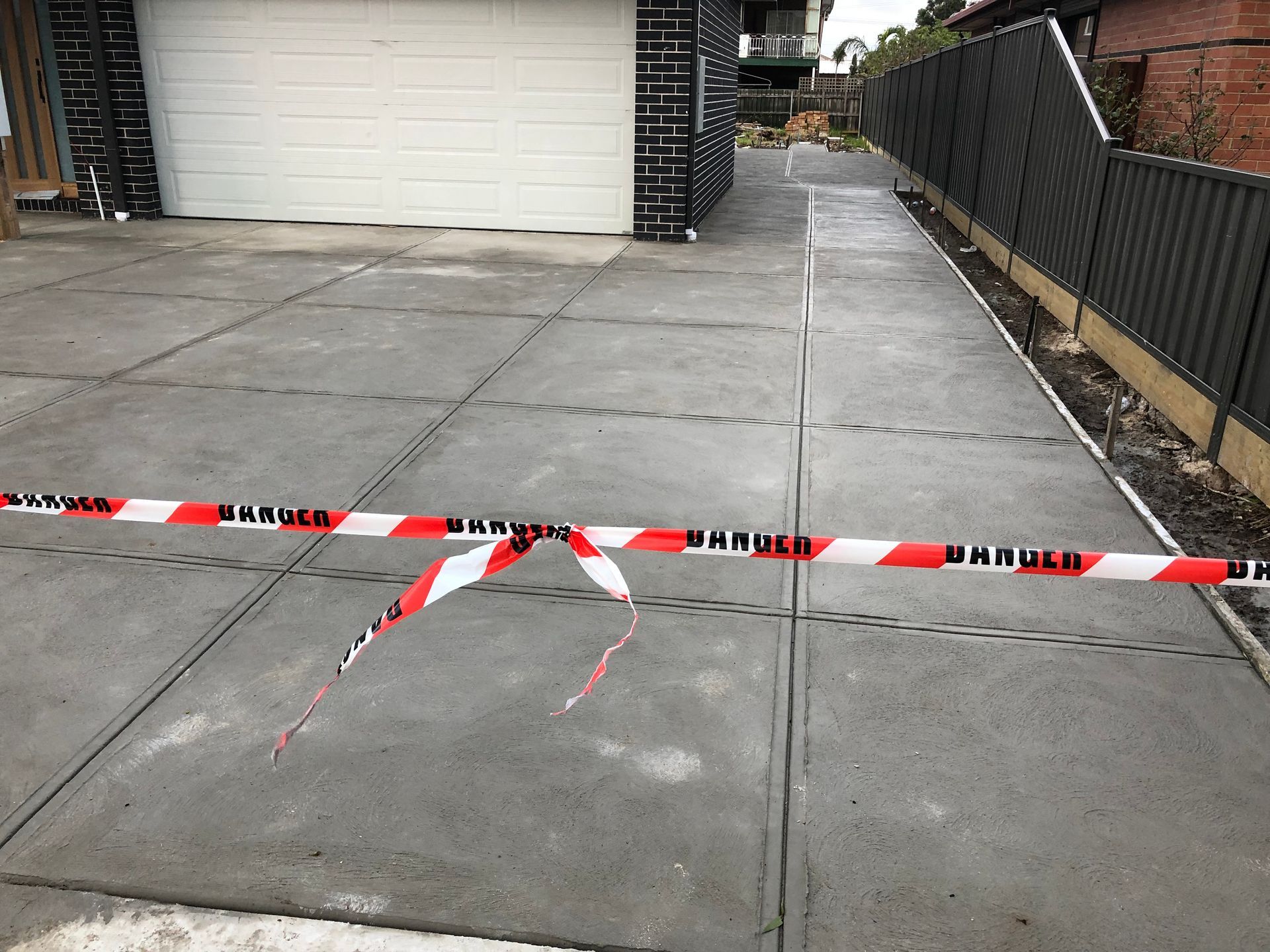 A concrete driveway with red and white tape on it.