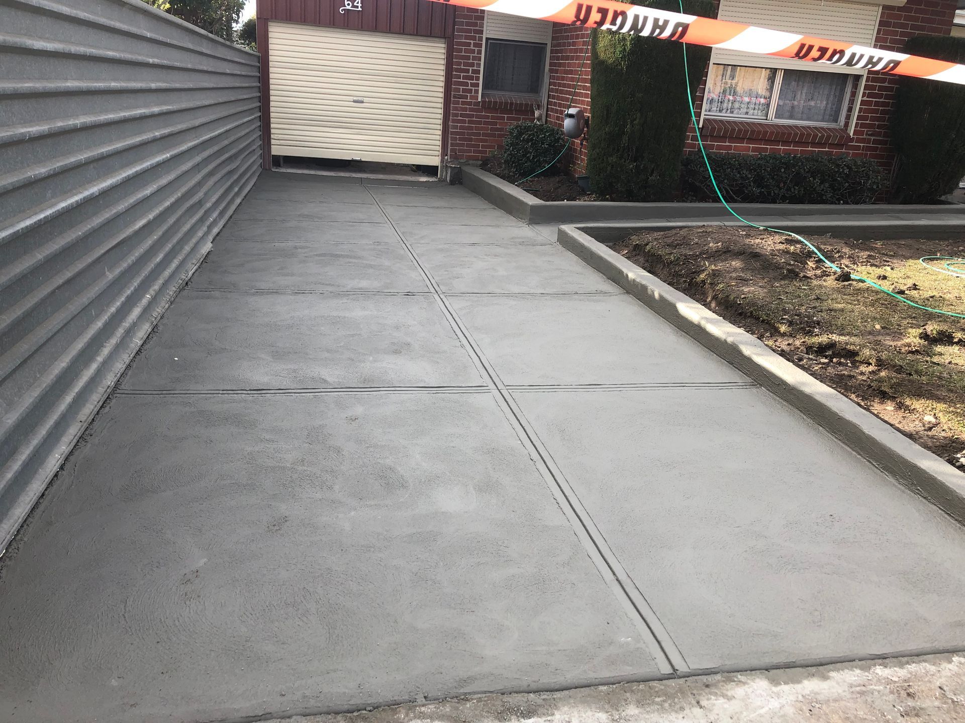 A concrete driveway leading to a garage next to a brick house.