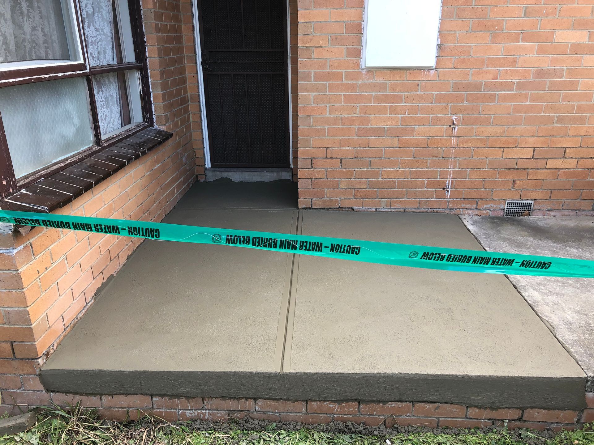 A concrete walkway is being built in front of a brick building