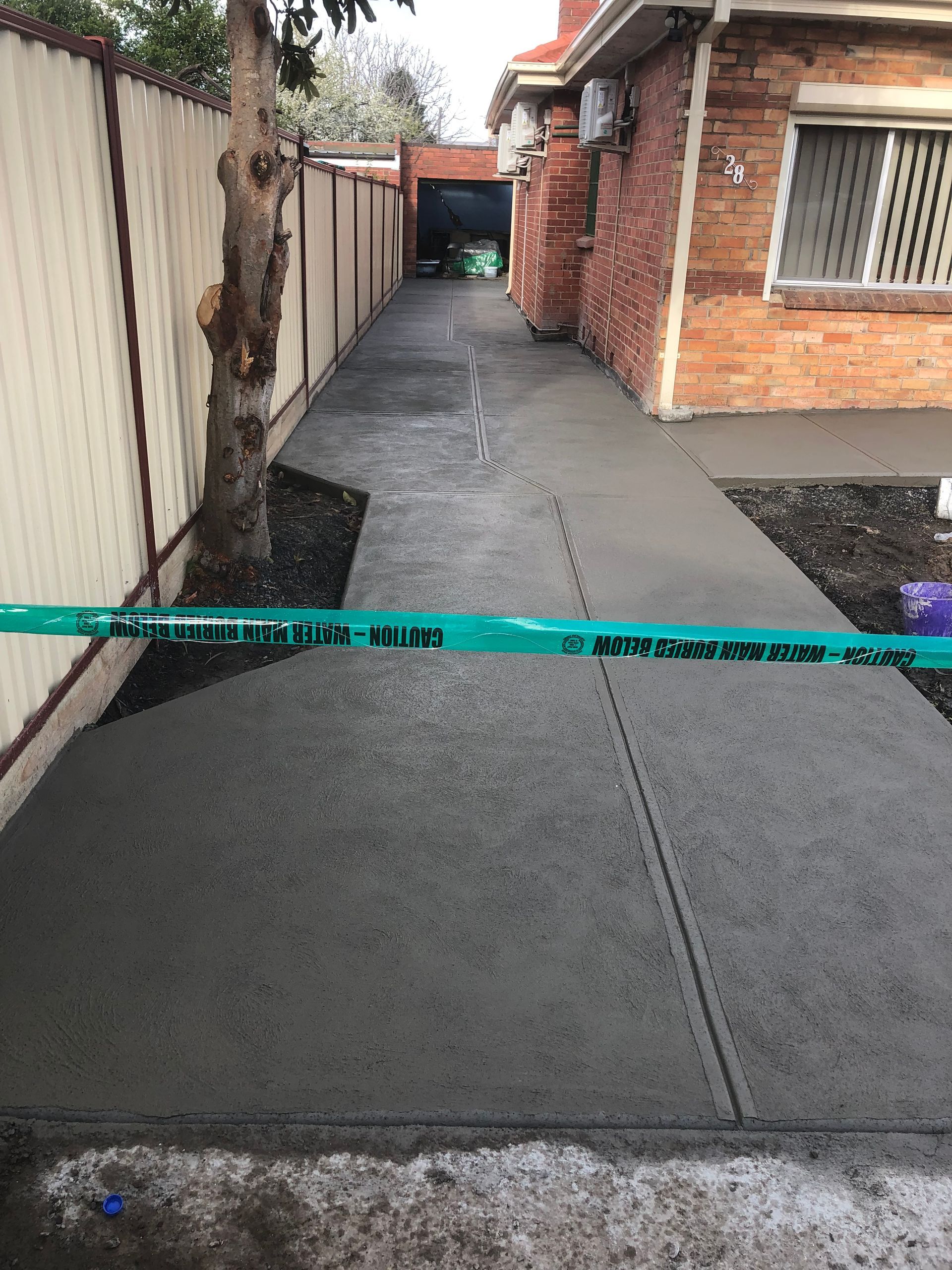 A concrete walkway is being built in front of a brick house.