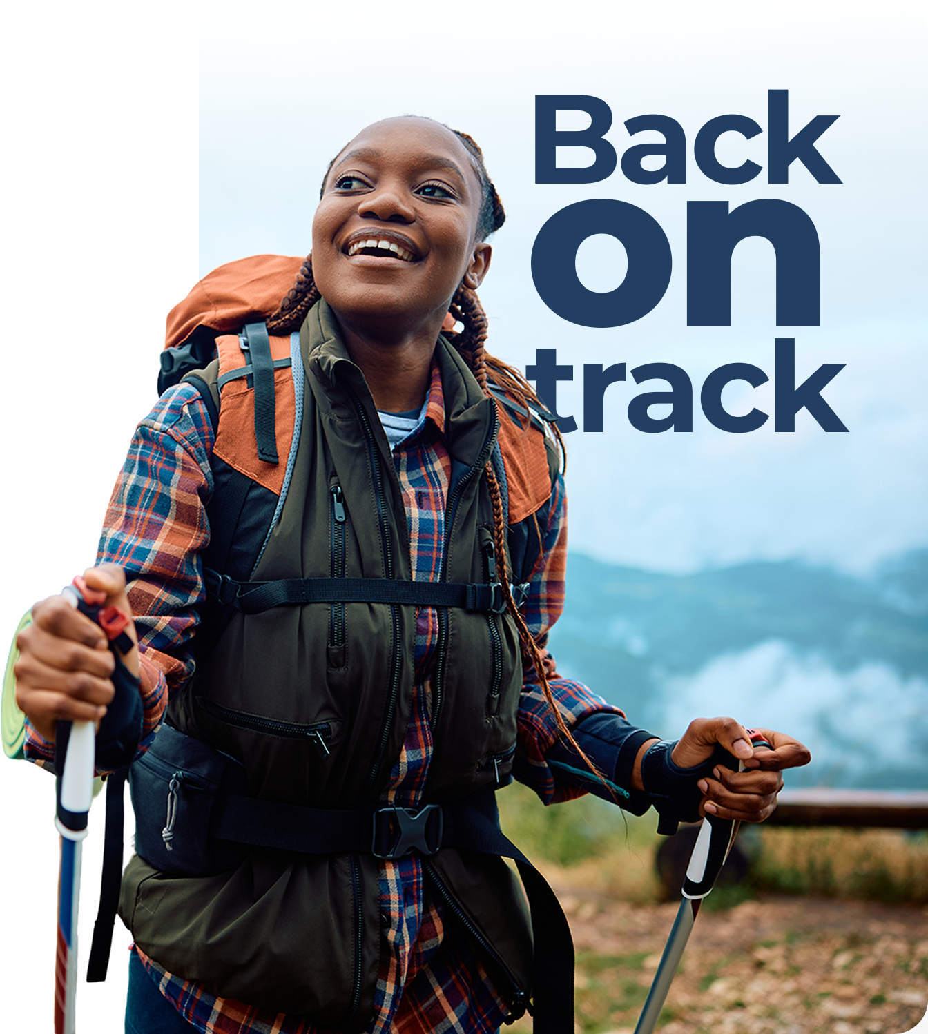 A woman with a backpack and hiking poles is smiling.