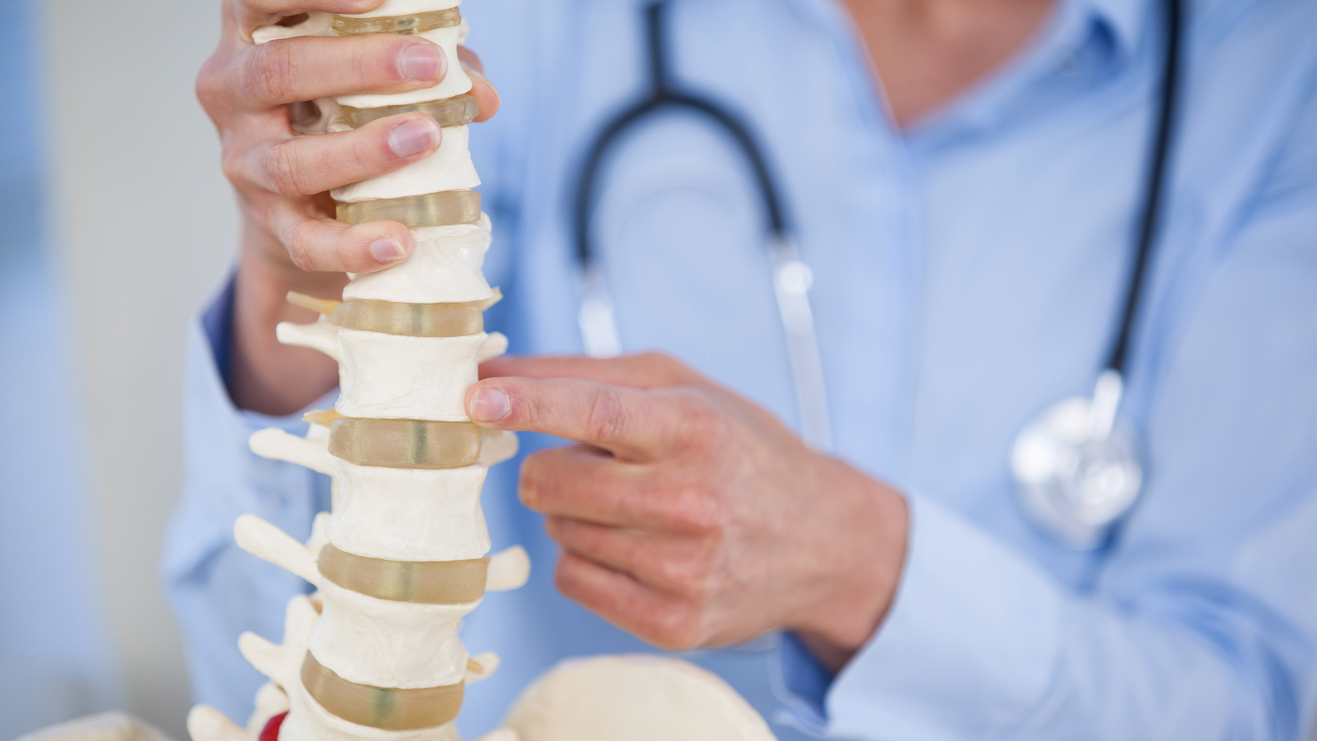 Doctor pointing to a spine model, explaining its structure.