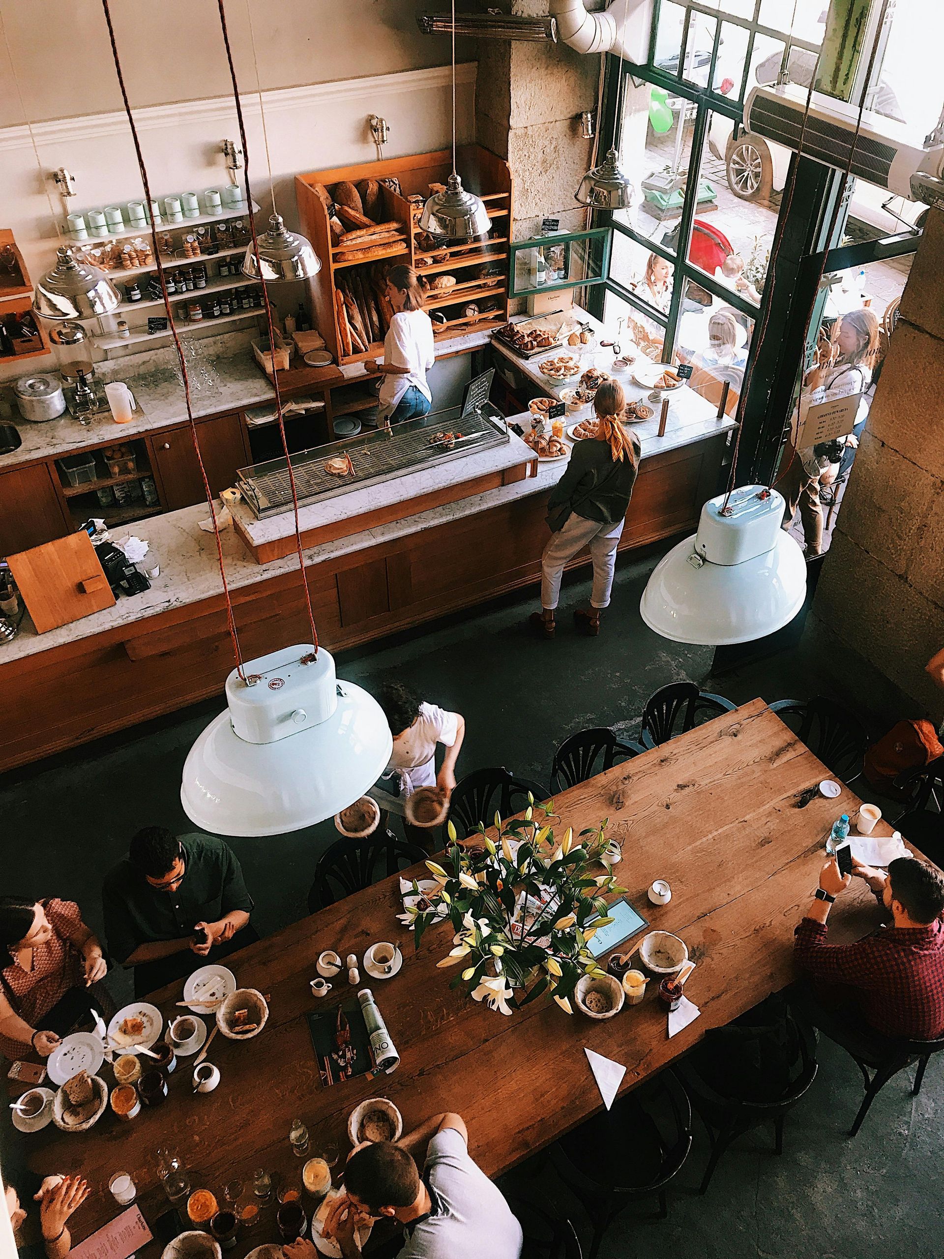 A group of people are sitting at a long wooden table in a restaurant.