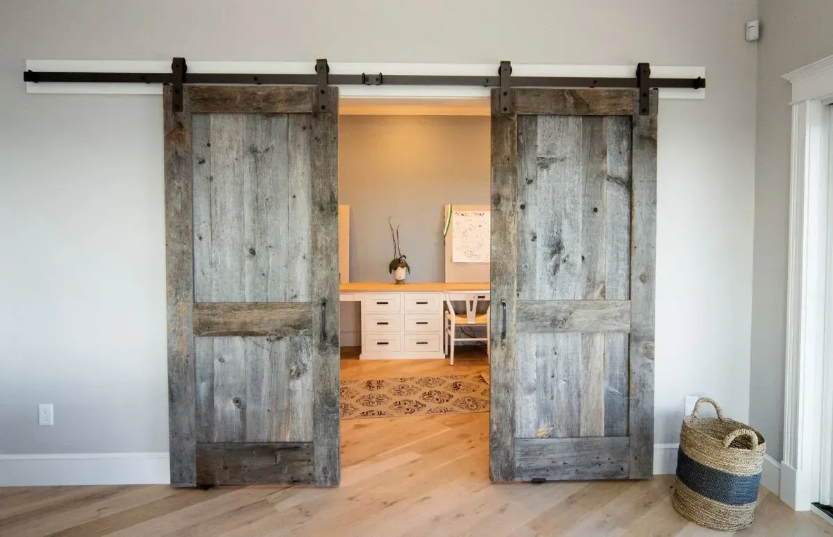 A room with sliding barn doors leading to a home office.
