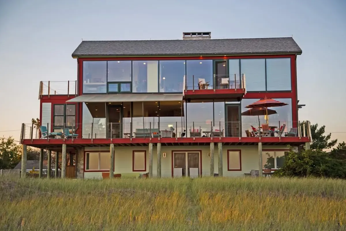 A large house with a lot of windows is sitting in the middle of a field.