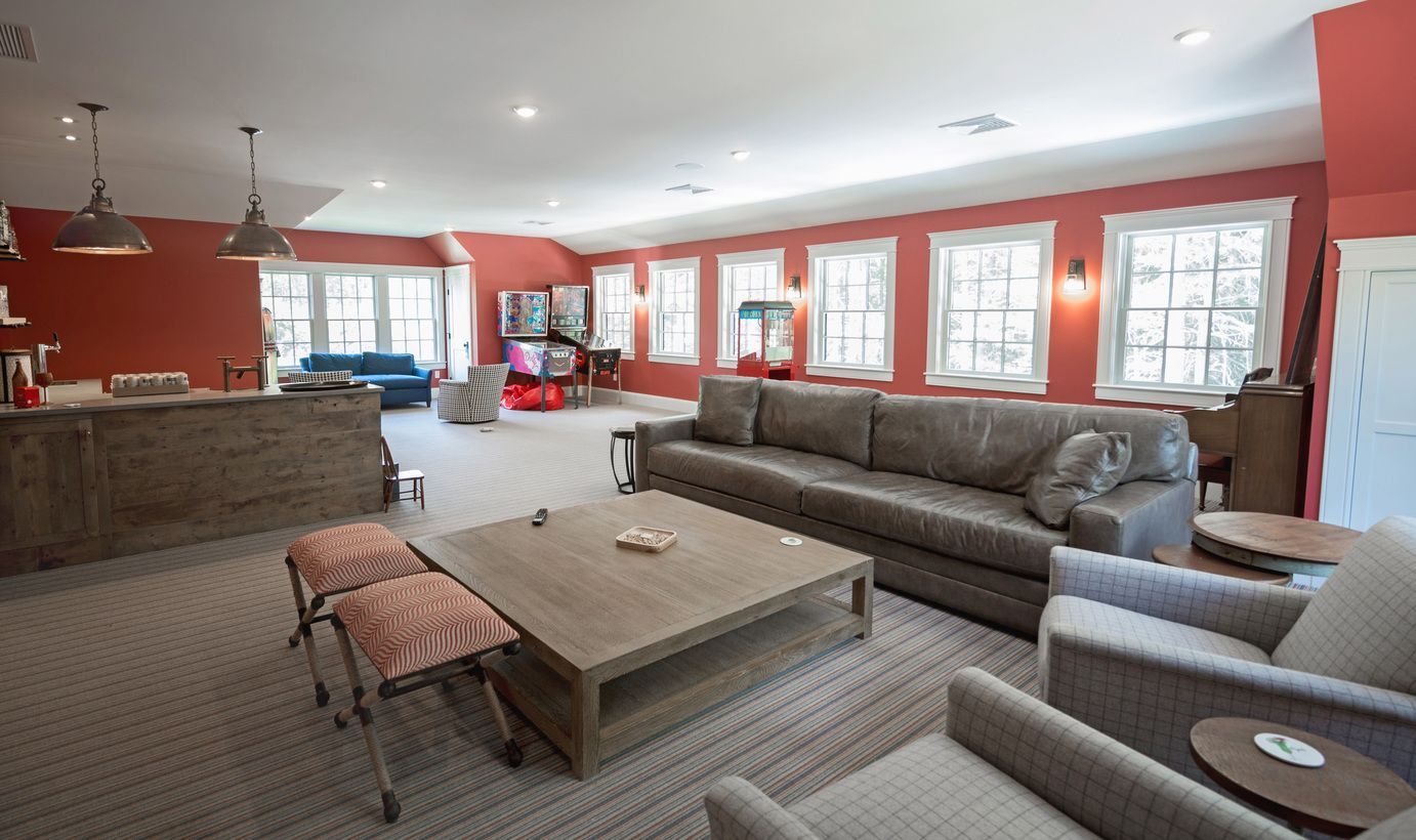 A living room with a couch , chairs , a table and a bar.