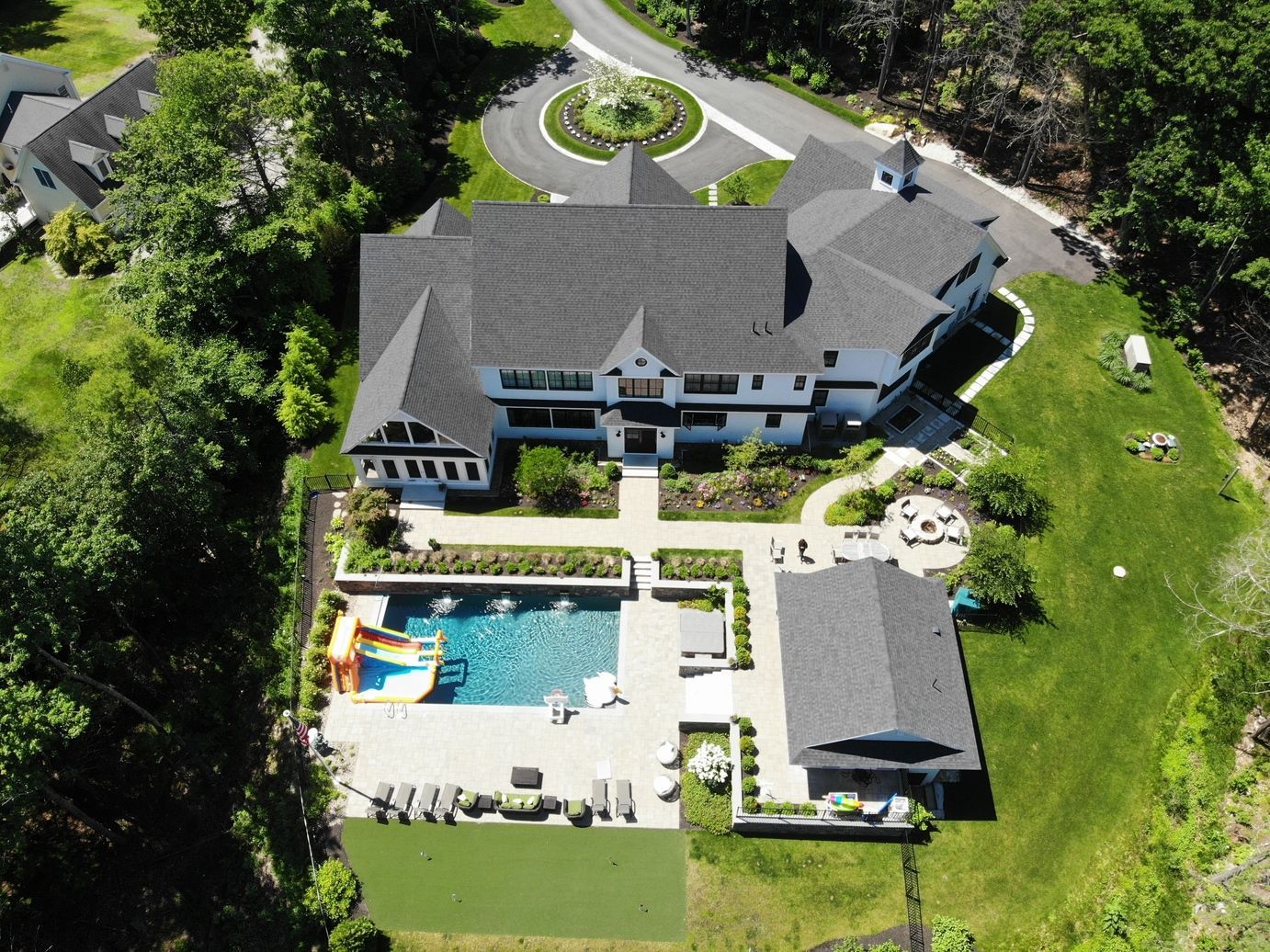 A large home with walkways and a pool with green pretty grounds