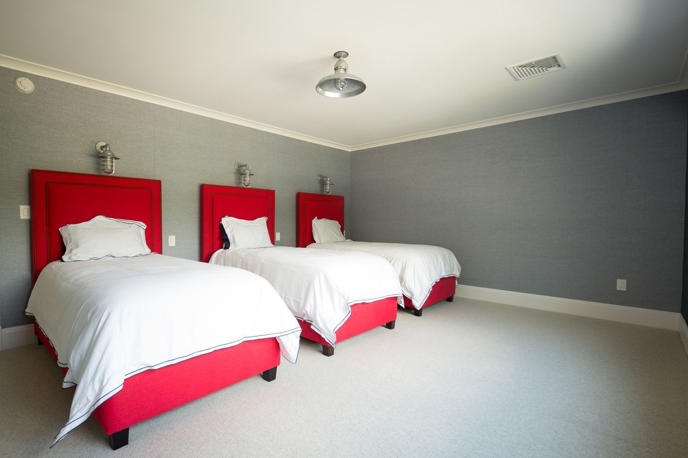 A bedroom with three beds and a projector on the ceiling