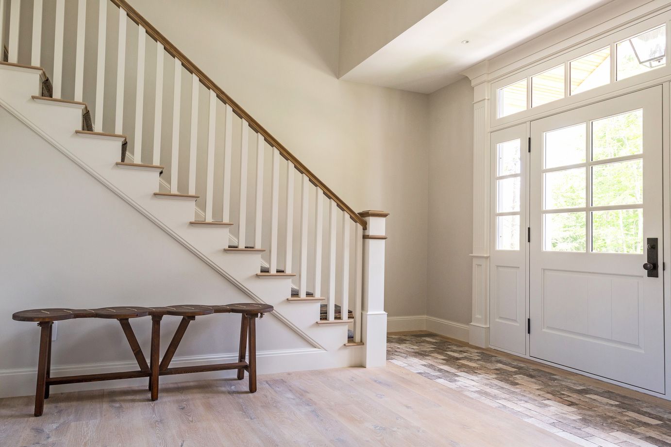 There is a bench under the stairs in the hallway.