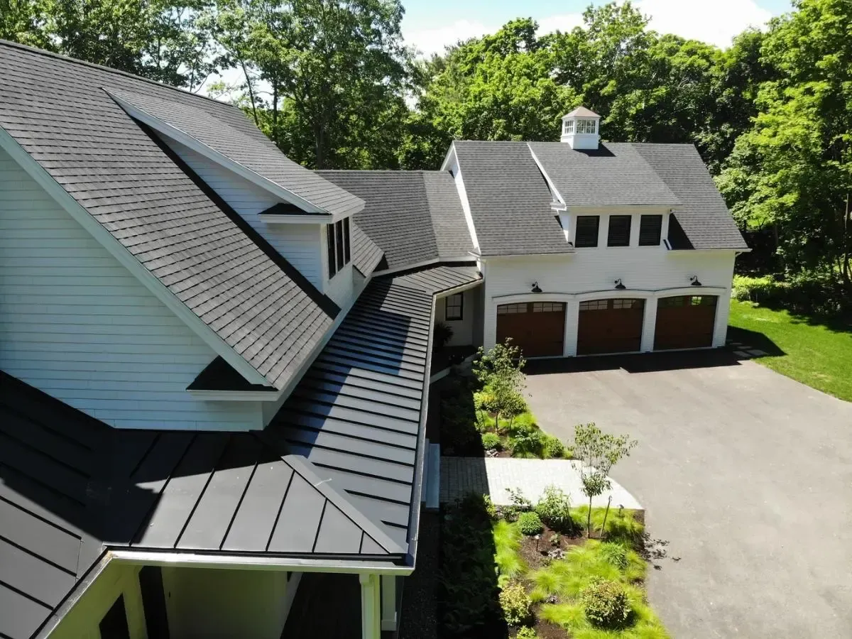 An aerial view of a white house with a black roof