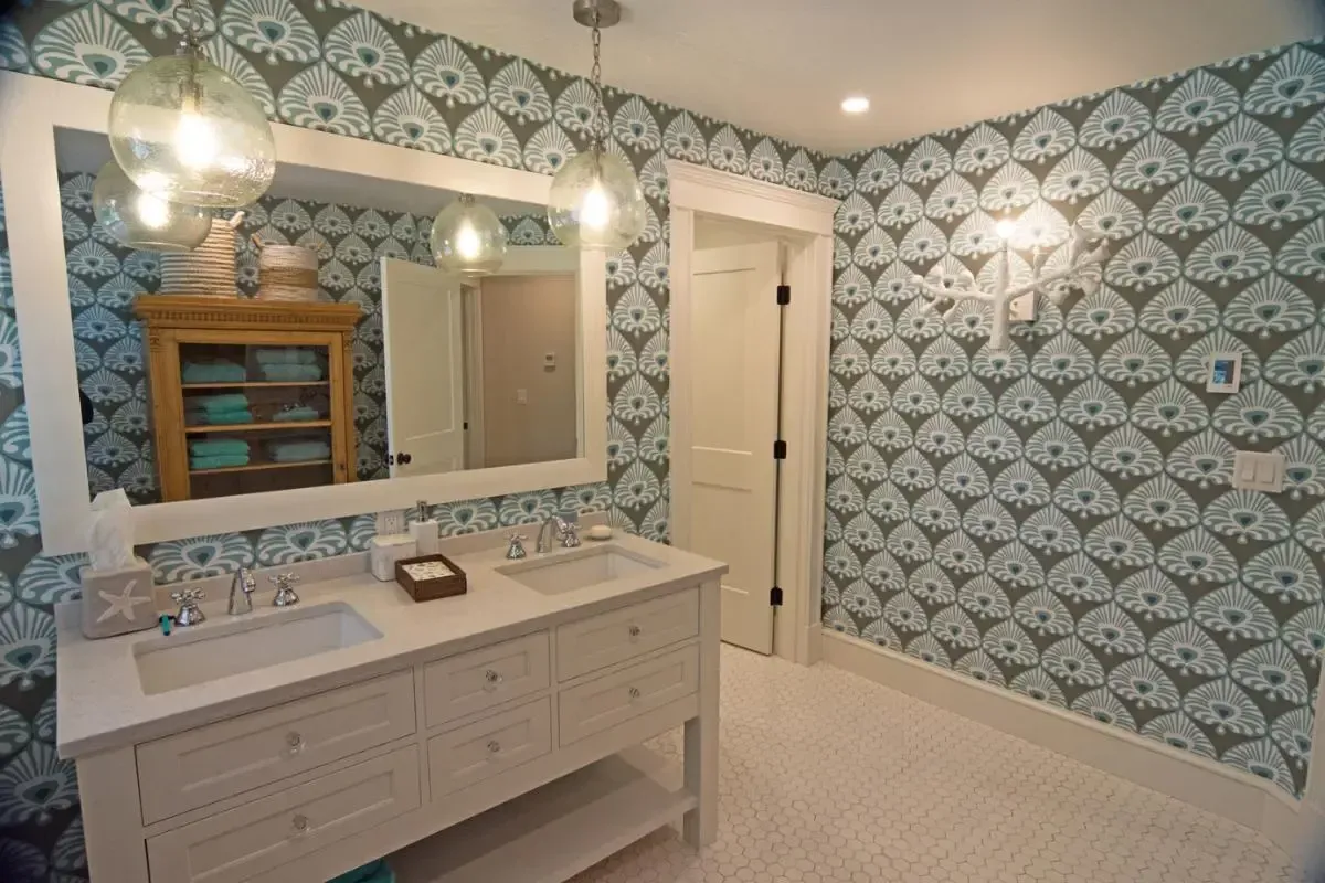 A bathroom with two sinks , a mirror , and blue and white wallpaper.
