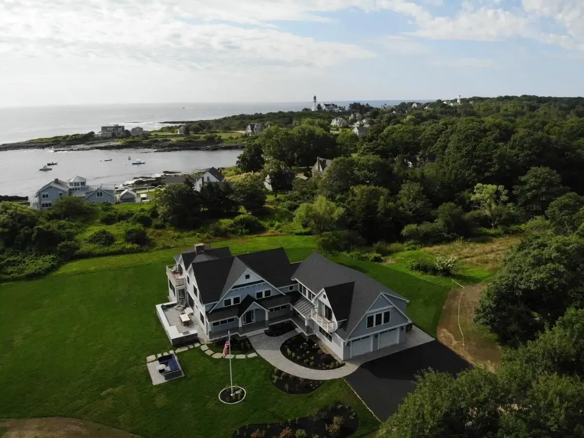 An aerial view of a large house surrounded by trees and a body of water.