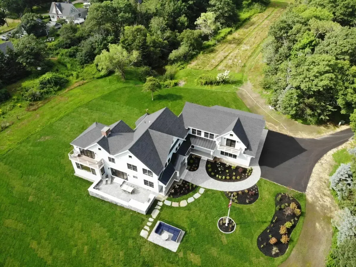 An aerial view of a large house surrounded by trees and grass.