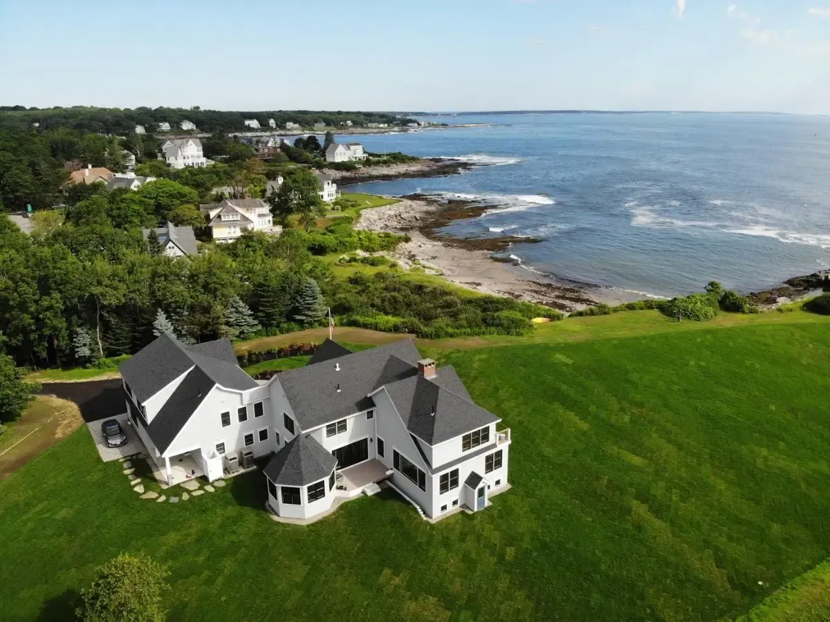 An aerial view of a house on a hill overlooking the ocean