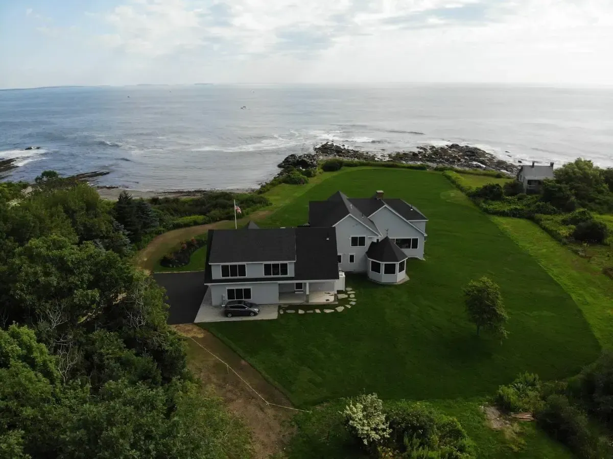 An aerial view of a house on a hill overlooking the ocean