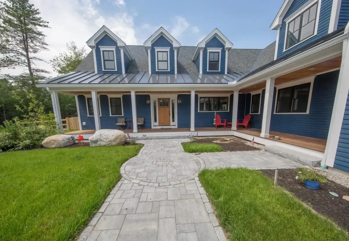 A large blue house with a brick walkway leading to it