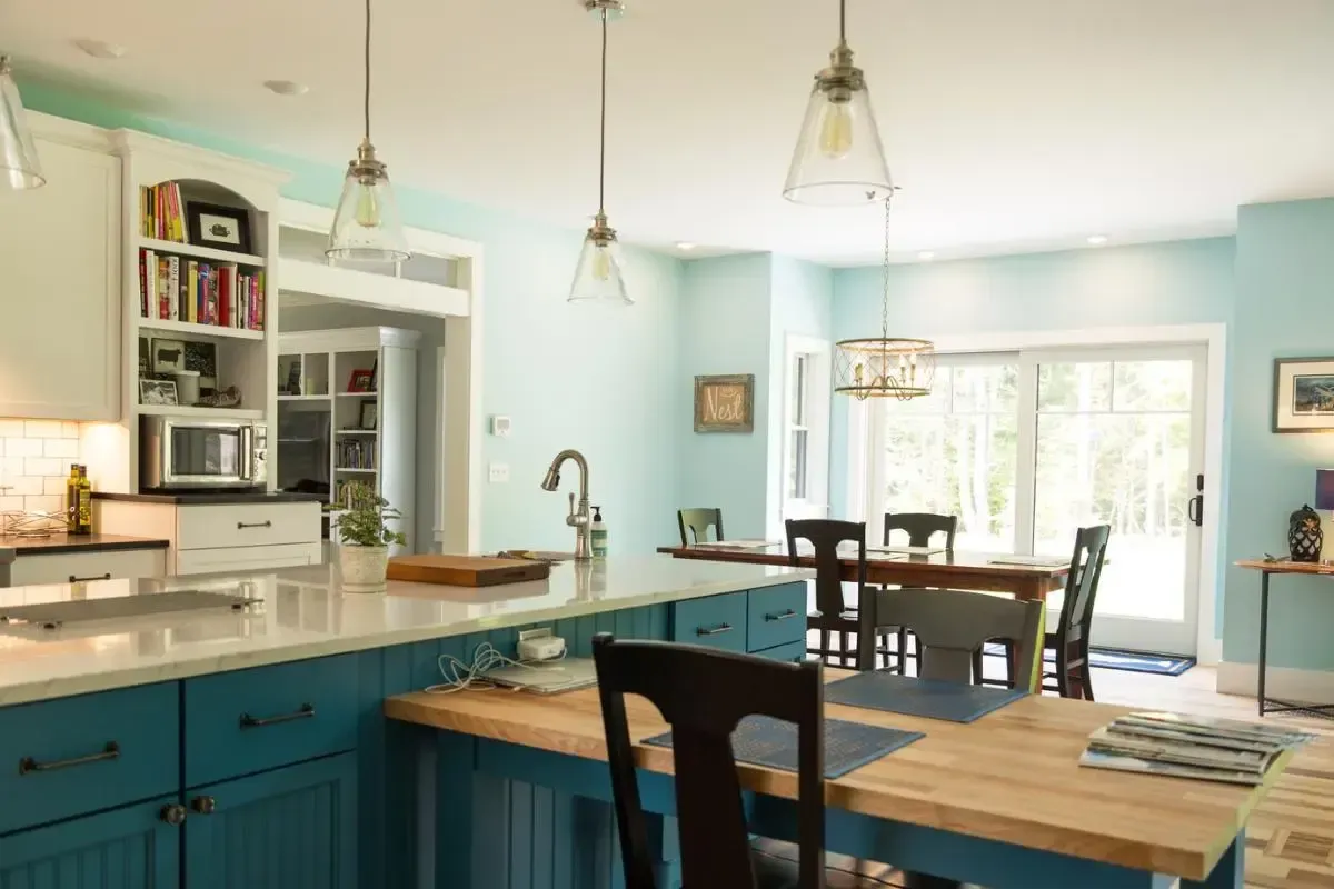 A kitchen with blue cabinets and a wooden table and chairs.