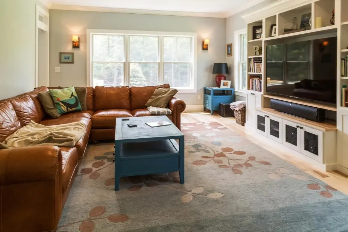 A living room with a brown sectional couch and a blue coffee table.