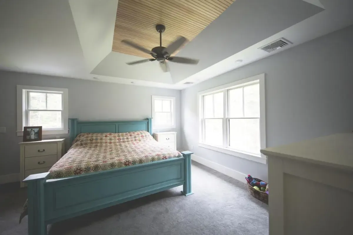 A bedroom with a blue bed and a ceiling fan