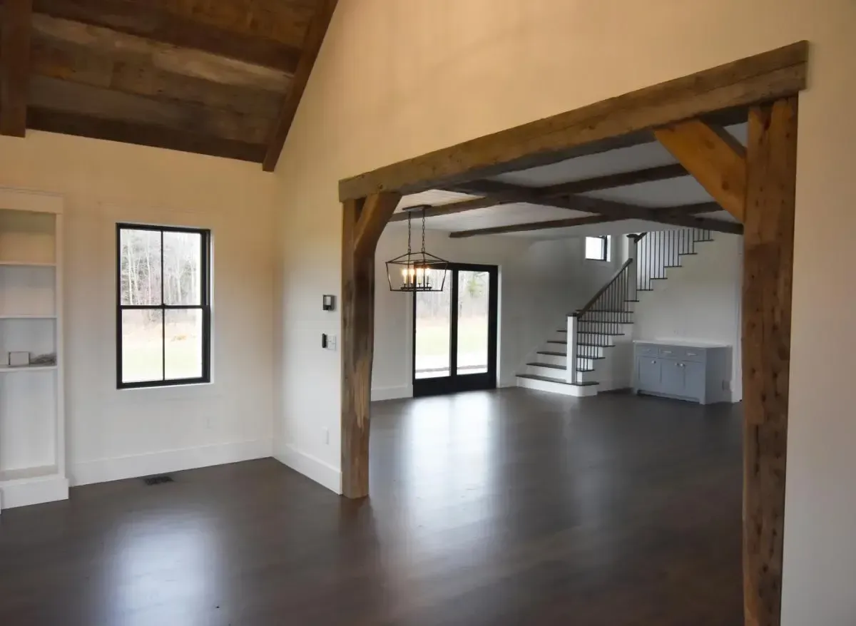 An empty room with wooden beams and a staircase in the background