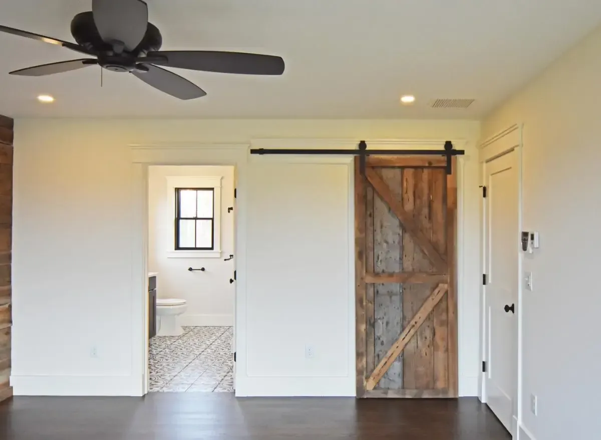 An empty room with a ceiling fan and a sliding barn door