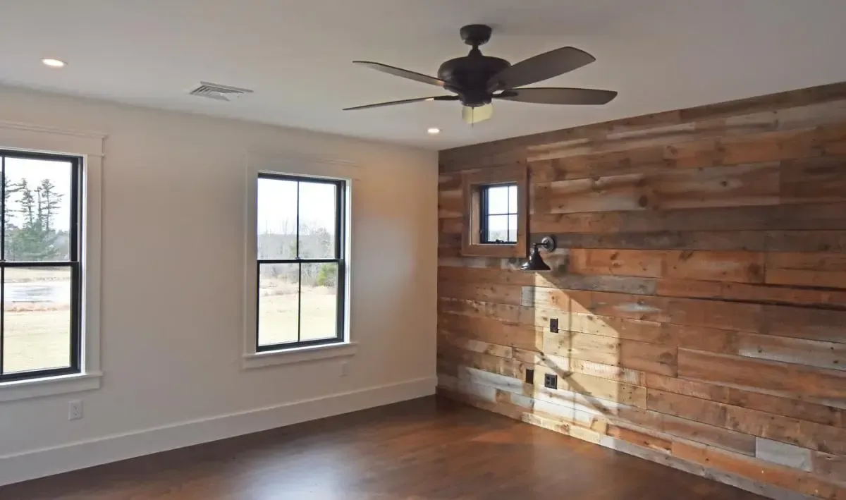 An empty room with a wooden wall and a ceiling fan.