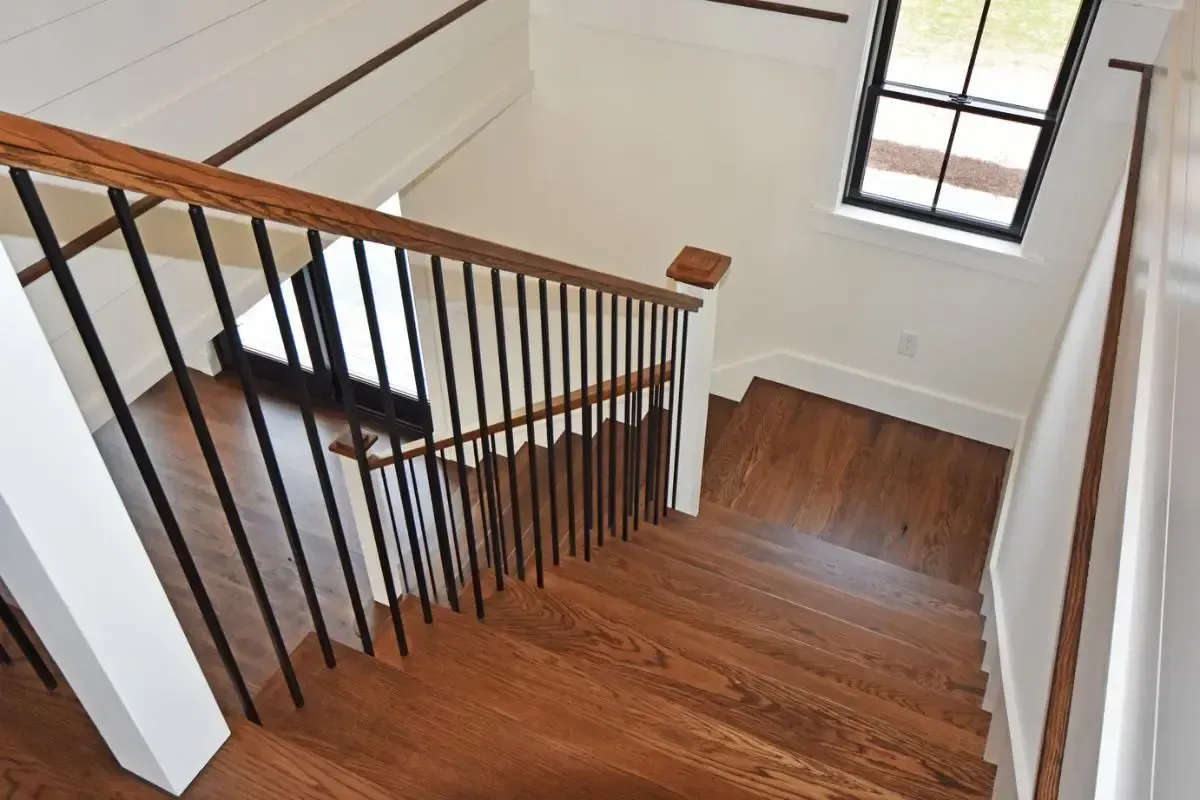 A wooden staircase with a black railing and a window.