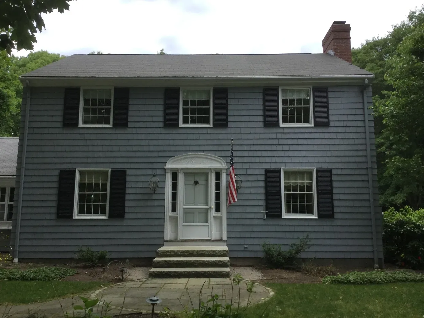 A blue house with black shutters and an american flag