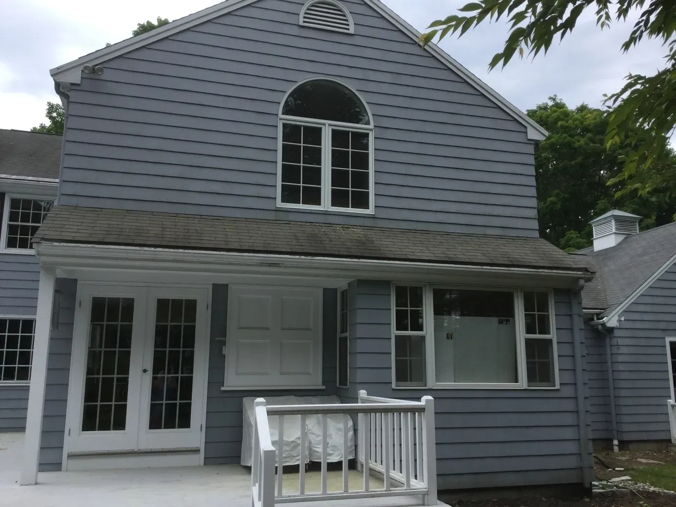 A blue house with a white porch and a gray roof