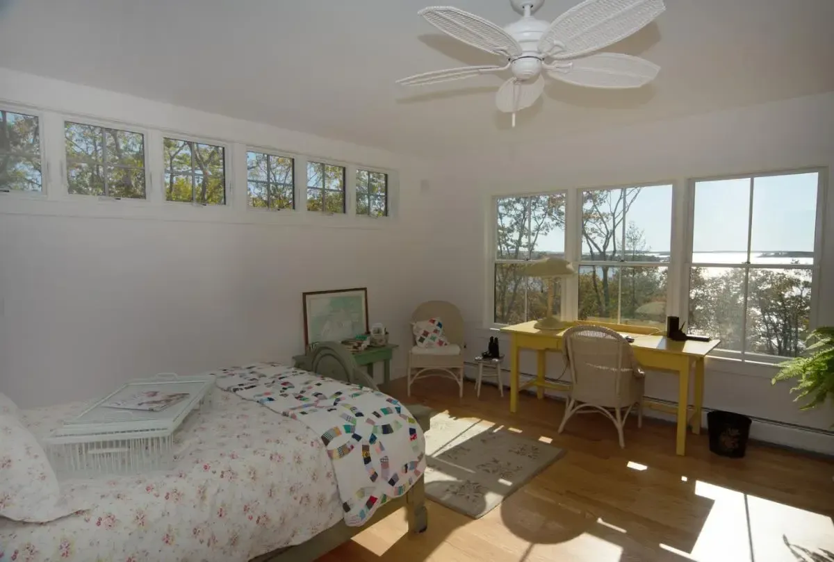 A bedroom with a bed a desk and a ceiling fan