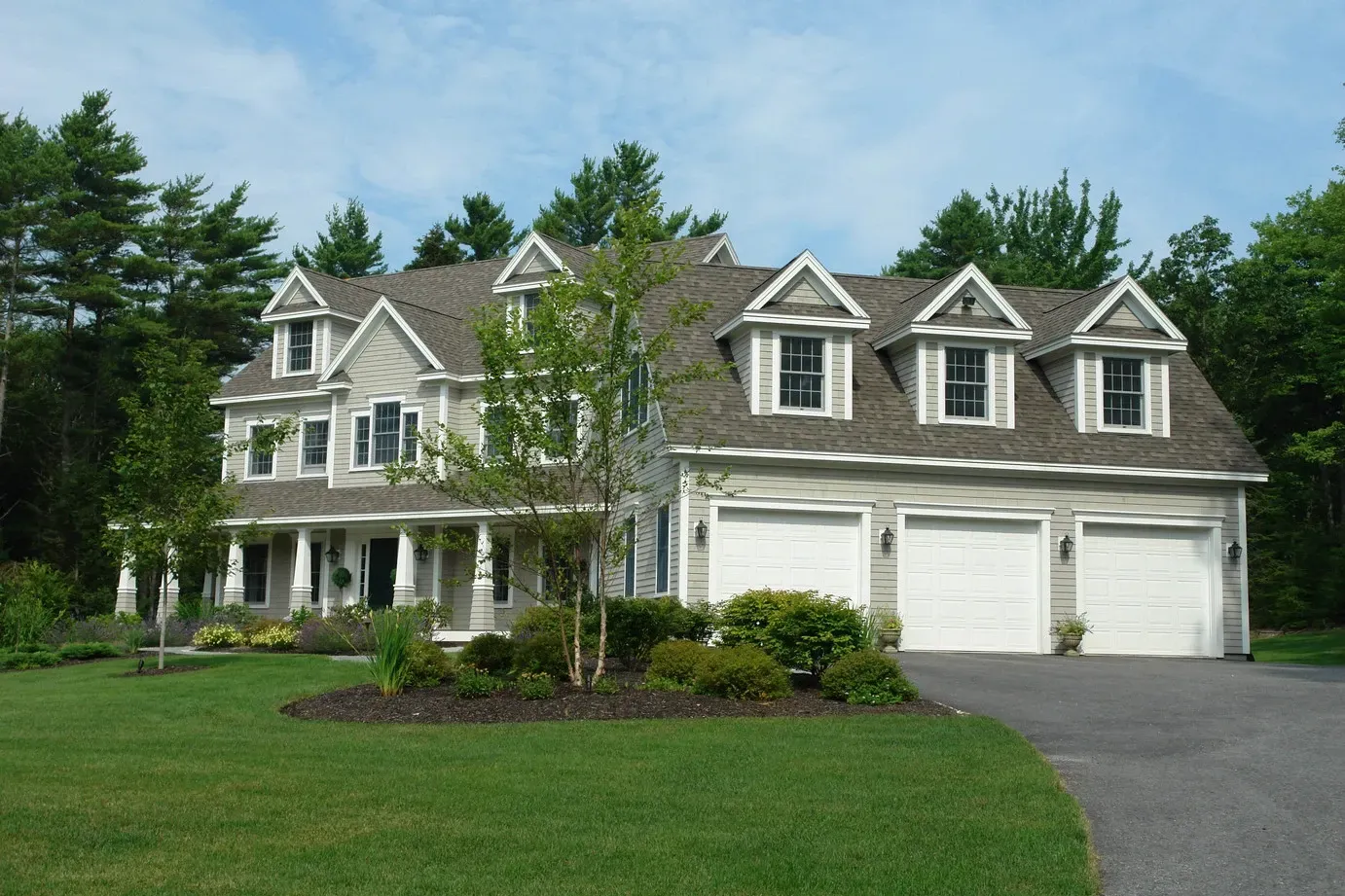 A large house with three garage doors and a driveway