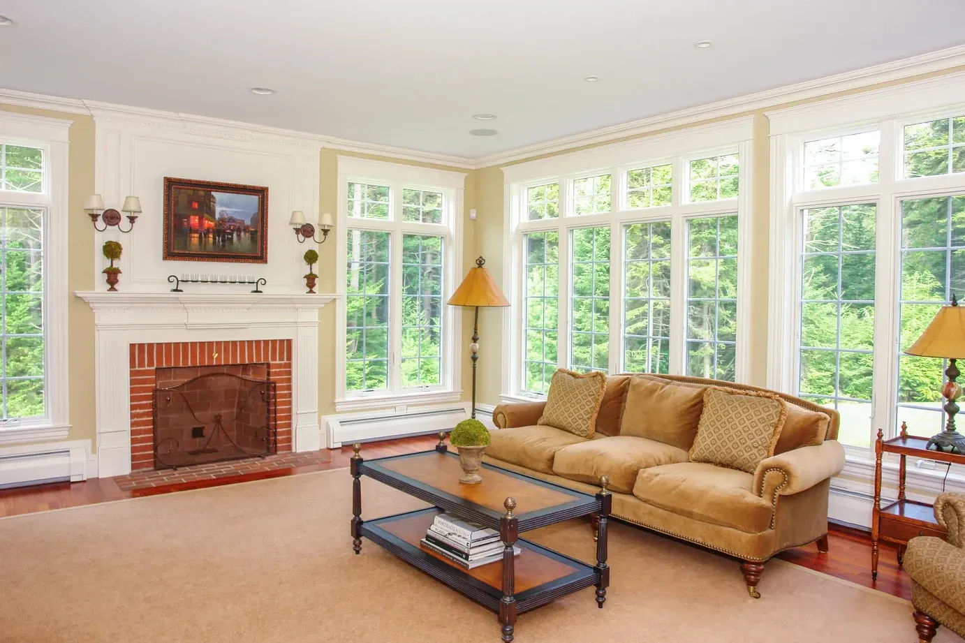 A living room with a couch , coffee table , fireplace and lots of windows