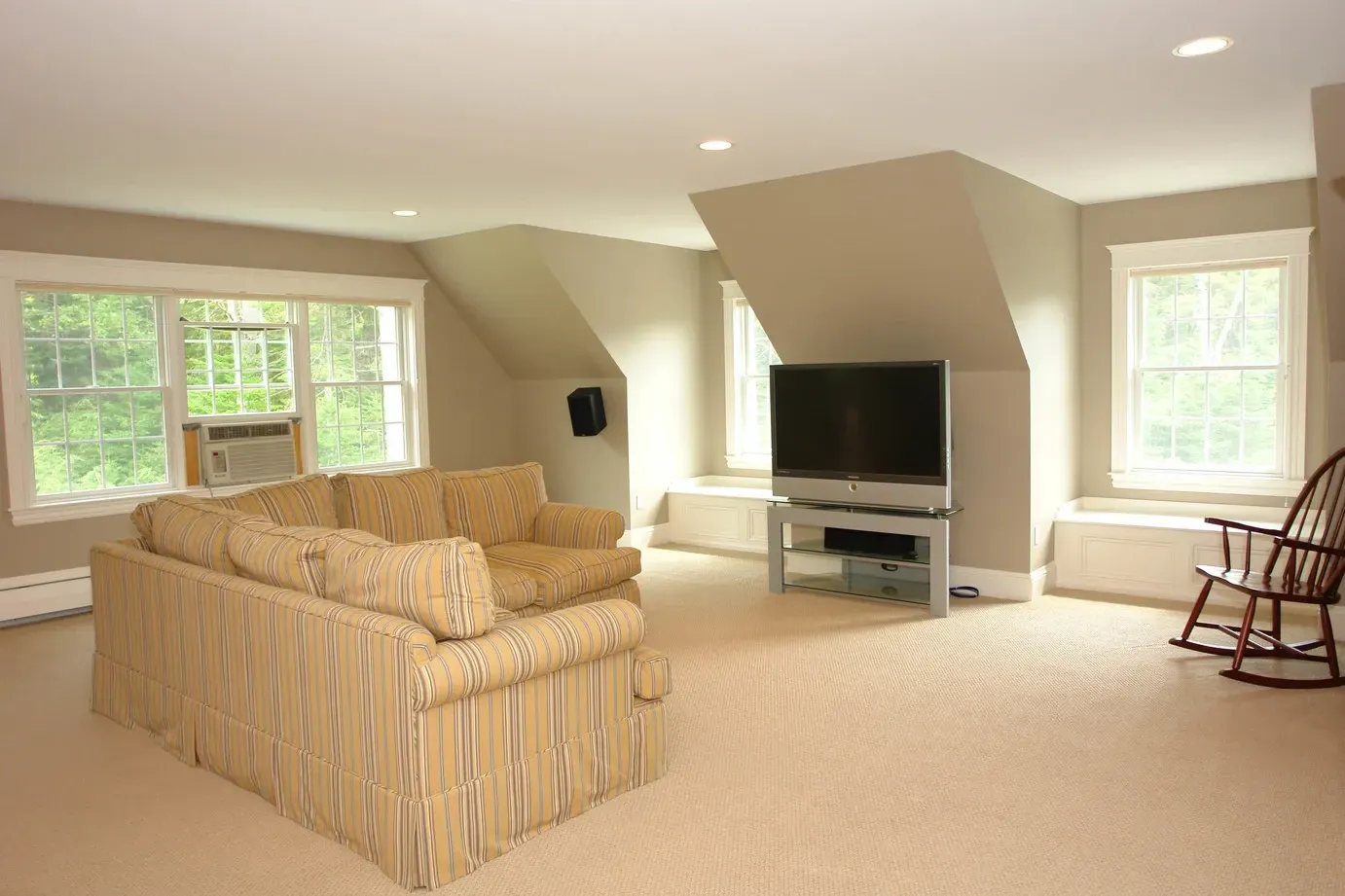 A living room with a couch , chair , television and rocking chair.